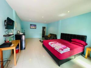 a bedroom with a large red bed and a television at Baan Sri Family in Kabin Buri