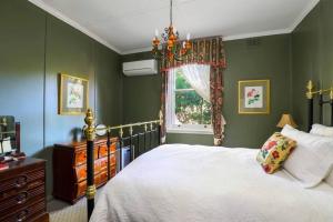 a bedroom with green walls and a bed and a window at Cherry Tree Cottage in Leura