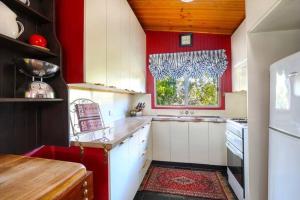 a kitchen with red walls and white cabinets and a window at Cherry Tree Cottage in Leura