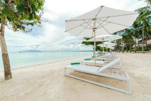 a row of lounge chairs and an umbrella on a beach at Modala Beach Resort in Panglao Island