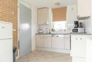 a kitchen with white cabinets and a brick wall at Bungalow 6 op Recreatiepark De Wielen in Sint Maarten