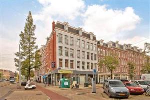 ein großes Gebäude an einer Stadtstraße mit parkenden Autos in der Unterkunft Charming apartment in city center in Amsterdam