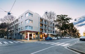 een wit gebouw in een stadsstraat met geparkeerde auto's bij Haven Glebe in Sydney