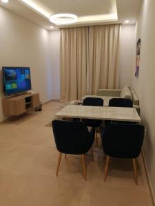 a room with a table and chairs and a television at JOOD RESIDENCE in Seef
