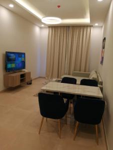 a room with a table and chairs and a television at JOOD RESIDENCE in Seef