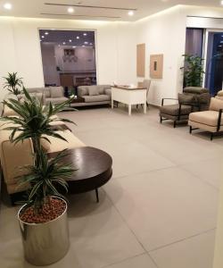 a lobby with couches and a table and a palm tree at JOOD RESIDENCE in Seef