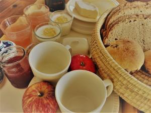 stół z chlebem, jabłkami, kubkami i innymi produktami spożywczymi w obiekcie Les2sources Bike-B&B w mieście Rochefort