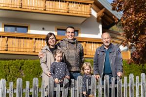 uma família atrás de uma cerca em frente a uma casa em Gästehaus Schwaiger em Sankt Michael im Lungau