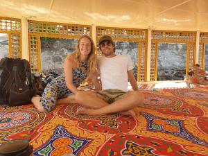 un hombre y una mujer sentados en una cama en Bob Marley Guest House en Asuán