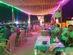 un grupo de personas sentadas en las mesas de una azotea por la noche en Bob Marley Guest House en Asuán