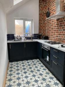 a kitchen with black cabinets and a tile floor at Beachside Bliss! in St. Leonards