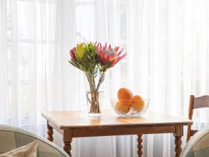 un jarrón de flores y naranjas sobre una mesa de madera en Woodys & Swallows Nest Cottages, en Himeville