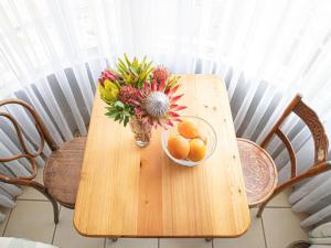 una mesa de madera con un jarrón de flores y naranjas. en Woodys & Swallows Nest Cottages, en Himeville