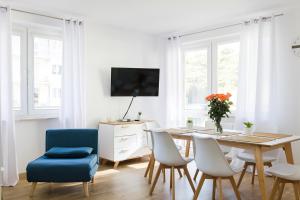 uma sala de estar branca com uma mesa de jantar e cadeiras em Apartamenty Bałtyckie - Na Wydmie - winda, bezpłatny parking, 100m od port em Ustka