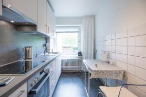 a kitchen with white cabinets and a table in it at Utsicht in Halebüll