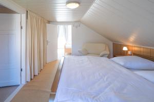 a bedroom with a large white bed and a chair at Sputnik in Nordstrand