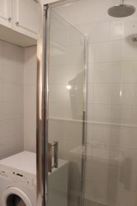 a glass shower in a bathroom with a washing machine at Rooms Gdańsk Wrzeszcz centrum in Gdańsk +42 photos