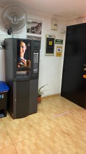 uma máquina de venda automática com uma televisão numa sala em PENSIÓN ROSA em Benidorm