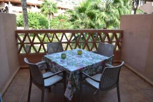 a table and chairs on a balcony with palm trees at Apartementos Almerimar Golf in Almerimar