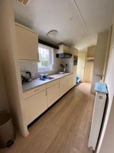 a large kitchen with white cabinets and a window at Chalet Togo in Wageningen