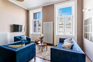 een woonkamer met twee blauwe banken en twee ramen bij Venus Apartments - Italian Stylish in Boedapest