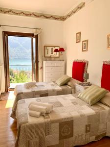 two beds in a room with a large window at La Dolce Vista in Tremezzo