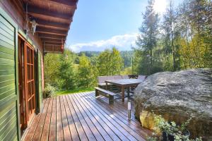 a wooden deck with a bench and a large rock at Chata Przesieka in Przesieka