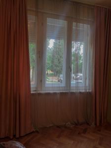 Habitación con 2 ventanas grandes con cortinas blancas. en Center 1 Podgorica, en Podgorica