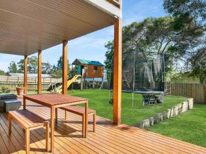 une terrasse en bois avec une table de pique-nique et une balançoire dans l'établissement The Bay House, à Corinella