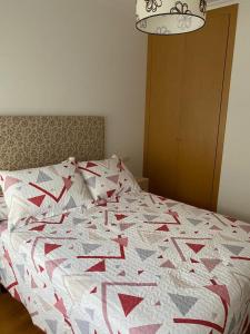 Una cama con un edredón rojo y blanco. en Piso Vista os castelos, en Viveiro