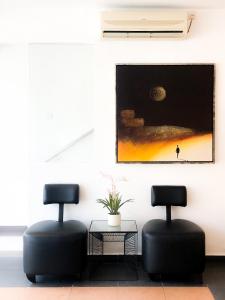 2 Stühle und ein Tisch in einem Zimmer mit einem Gemälde in der Unterkunft HAKO XPRESS TMN SKUDAI BARU in Skudai