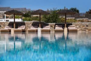 a swimming pool with umbrellas and lounge chairs and a pool at Ostria Inn in Moutsoúna