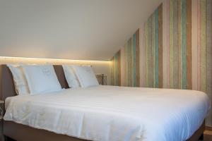 duże łóżko z białą pościelą i poduszkami w obiekcie B&B Orgel Thuis w mieście Kinrooi