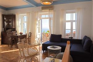 a living room with a blue couch and a table and windows at cherry's home in Glossa