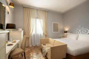Habitación de hotel con cama, silla y escritorio. en Alla Corte Delle Terme Resort, en Viterbo