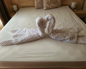 two swans are sitting on a bed with towels at Elegantz Apartments LaMer in Varna City