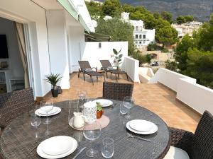 uma mesa com pratos e copos numa varanda em Ama Vida Altea apartment with panoramic view em Altea