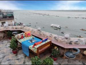 Shiva Ganges View Guest House في فاراناسي: شرفة مع طاولة وكراسي بجوار مجموعة من المياه