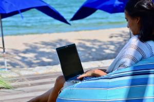 a woman sitting on a beach with a laptop at Sanae Beach Hua Hin in Khao Tao