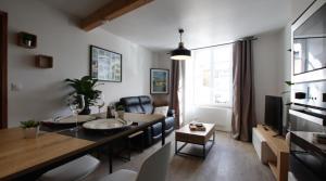 a living room with a dining table and a living room with a couch at Le Saint Pierre Quartier Historique d'Oloron Sainte Marie in Oloron-Sainte-Marie