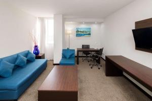 a living room with a blue couch and a desk at Wyndham Executivo Culiacan in Culiacán