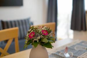 um vaso branco com flores cor-de-rosa sentado numa mesa em Haus Lowe Apartment Erdgeschoss 1 em Filzmoos