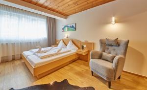 um quarto de hotel com uma cama e uma cadeira em Appartement Slope & Smile em Saalbach-Hinterglemm