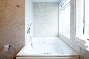 a white bath tub in a bathroom with a window at Fosshotel Stykkisholmur in Stykkishólmur