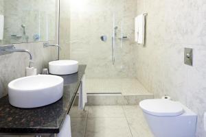 a white bathroom with two sinks and a shower at Fosshotel Stykkisholmur in Stykkishólmur