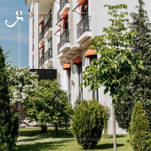 un edificio blanco con árboles delante de él en Hotel Garden, en Pristina