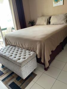 a large bed with a bench next to a window at Cityscape at Chelsea Manor / New Kingston Studio! in Kingston