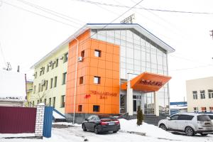 an orange building with cars parked in front of it at Готель Релакс in Korostyshiv