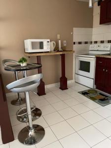 a kitchen with a microwave and a table with a stool at Cityscape at Chelsea Manor / New Kingston Studio! in Kingston