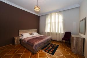 um quarto com uma cama, uma cadeira e uma janela em Red castle em Yerevan
